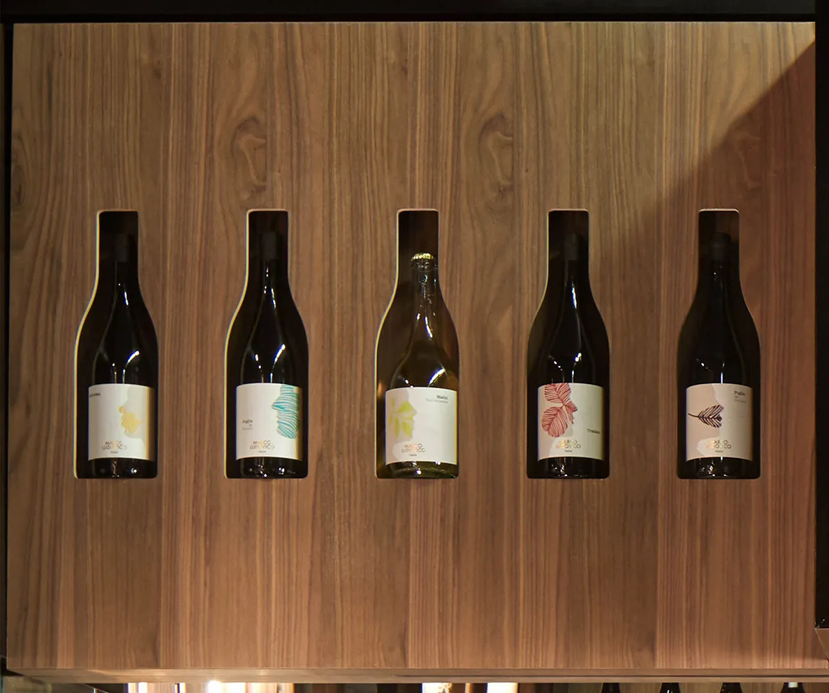 Espositore a muro Tosato 70.06 in noce canaletto con cinque bottiglie di vino in nicchie sagomate