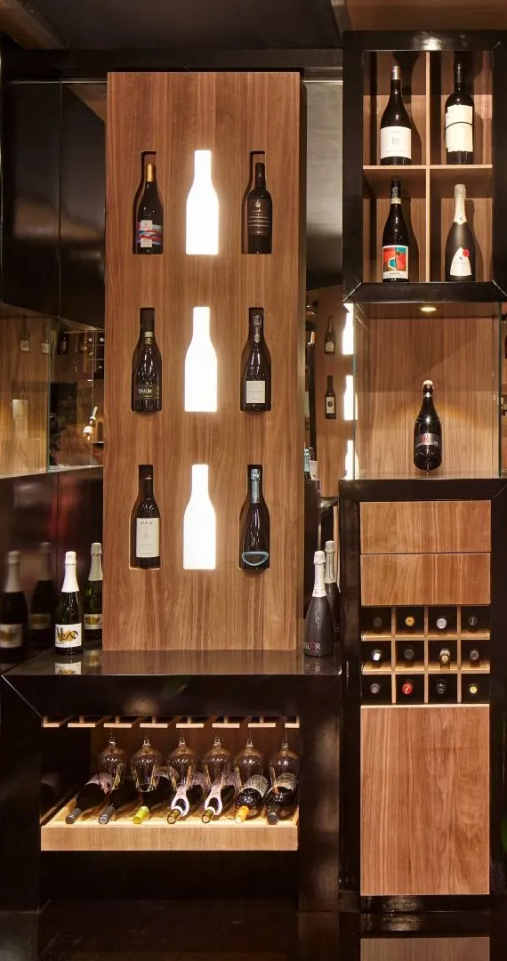 Espositore verticale Tosato 70.03 in noce con sei bottiglie e sagome luminose a LED, in un allestimento per il vino