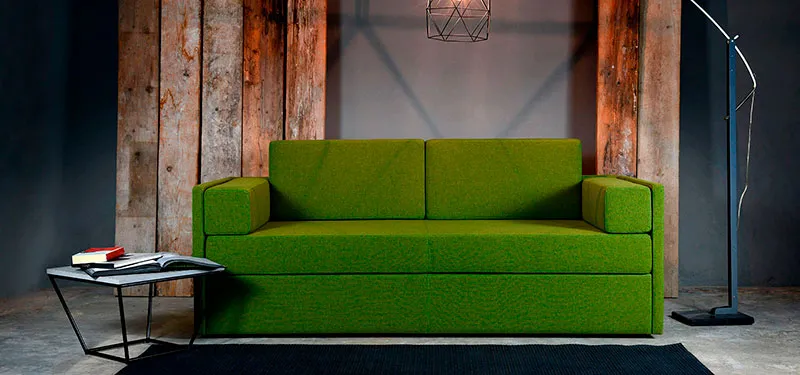 Divano letto Adria Domingo verde in un ambiente con parete in legno