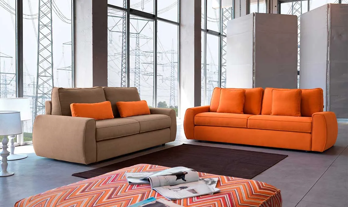 Due divani Shepard Domingo arancio e beige in un loft con vetrate