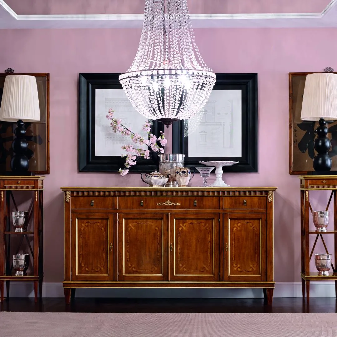Credenza Tosato 23.33 Gold in noce oro sotto un lampadario di cristallo, davanti a una parete rosa