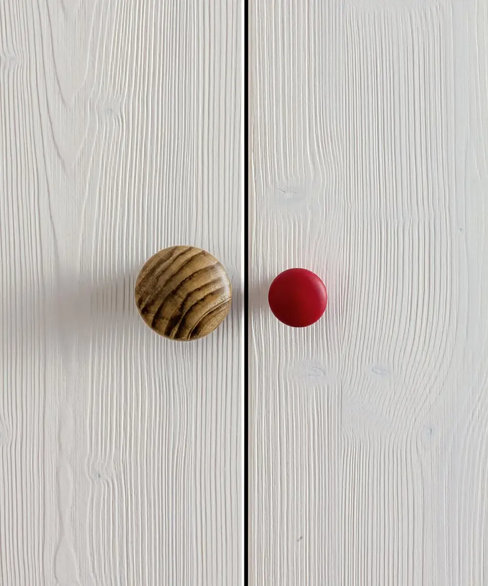 Pomelli tondi in legno rigato e rosso sulle ante bianche dell’armadio Easy Callesella