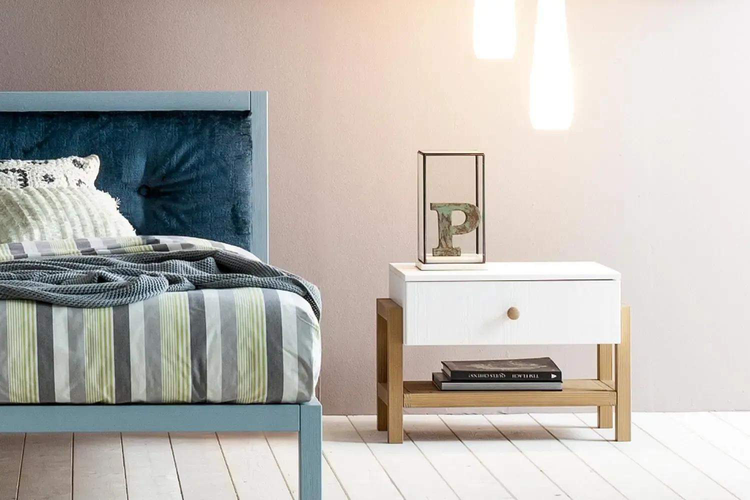 Comodino Argon Callesella bianco a un cassetto con fianchi in legno naturale accanto al letto