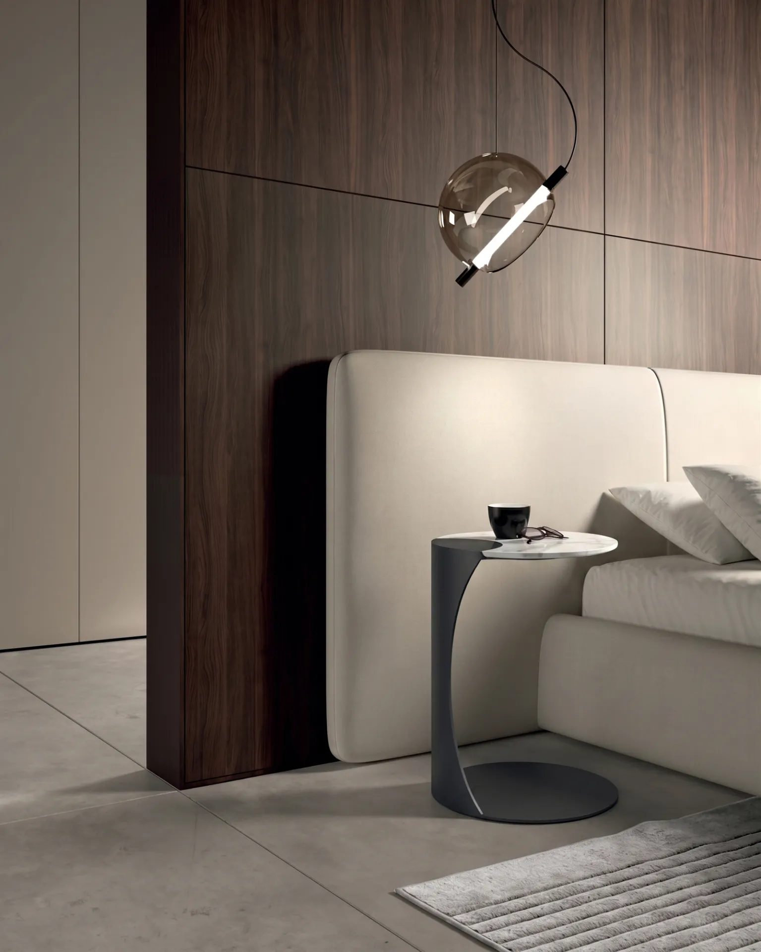 Tavolino Tee Stones in marmo bianco con stelo antracite accanto a un divano, sotto una lampada a sospensione