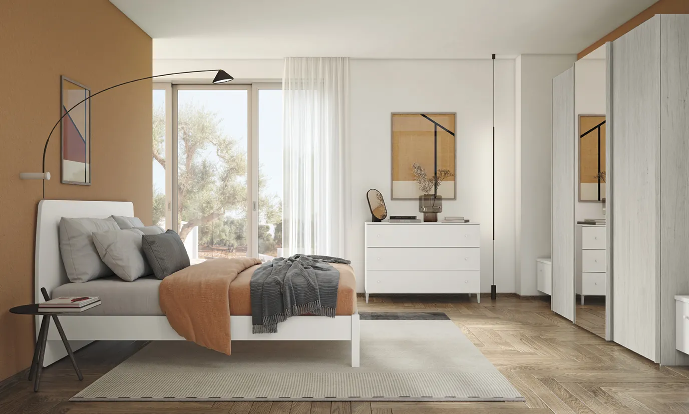 Letto con testata Soy Colombini bianco accanto a una parete terracotta e a un comò a cassetti