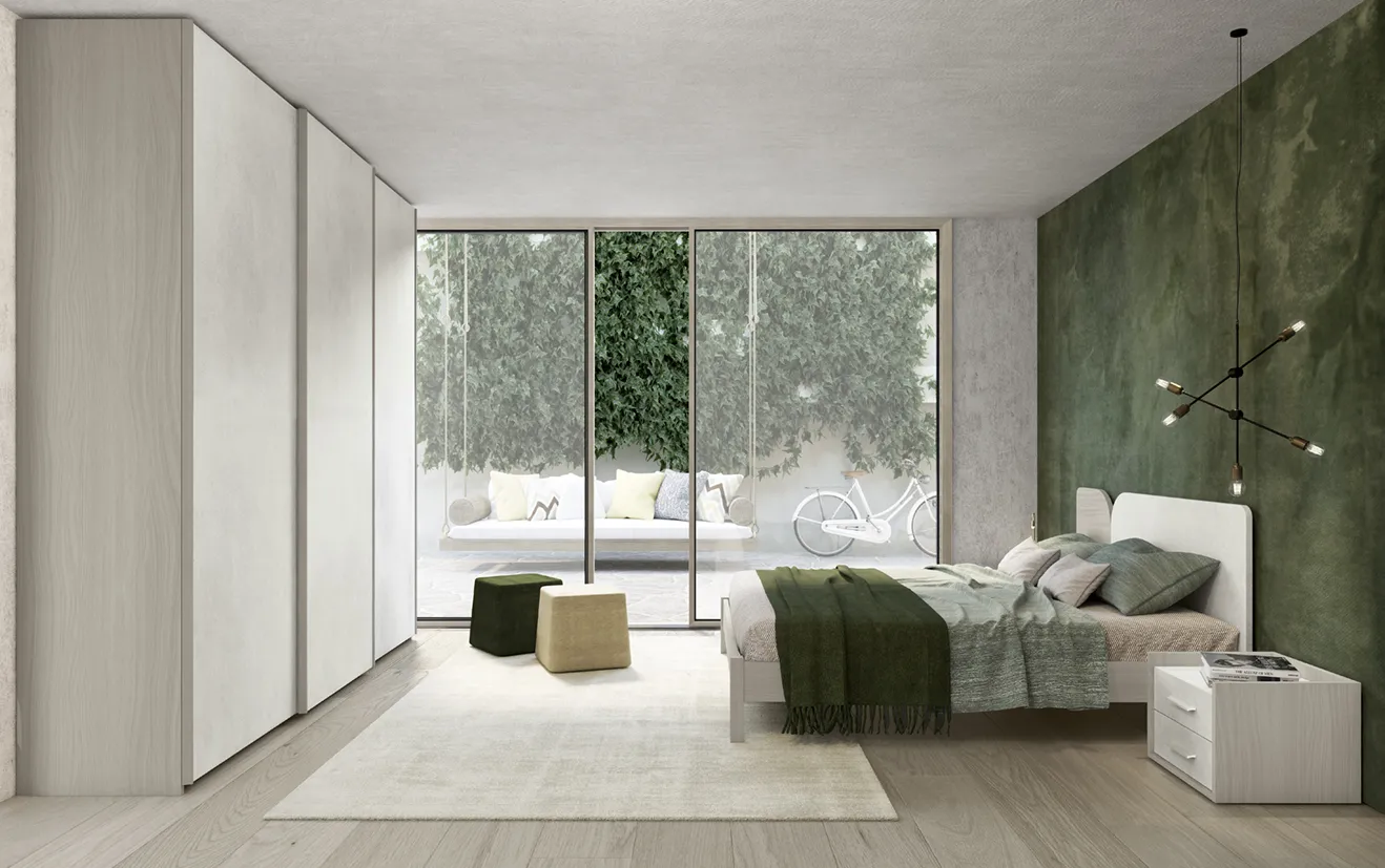 Letto con testata Tulip Colombini chiaro in una camera con parete verde muschio e armadio scorrevole