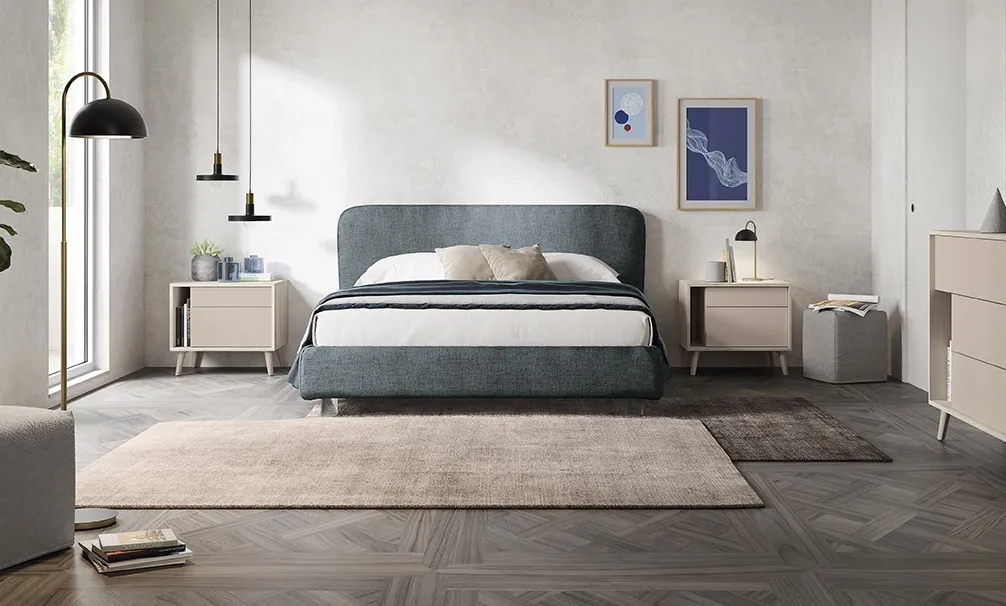 Letto imbottito Reverso Colombini blu polvere tra comodini chiari su gambe svasate
