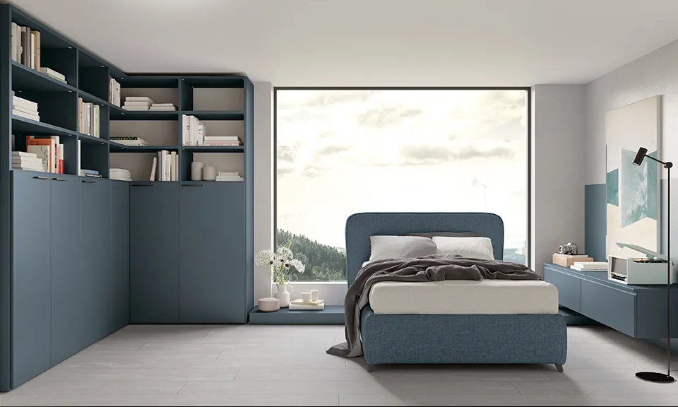 Letto singolo Reverso Colombini blu davanti a una grande finestra e a una parete di armadi blu