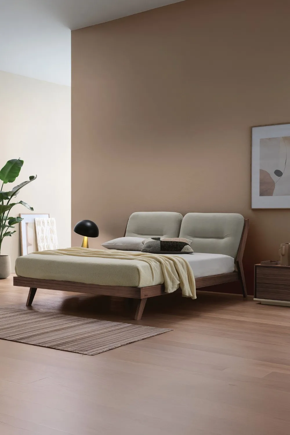Letto Sussurro Le Fablier con cuscini chiari in una camera dalle pareti color terra