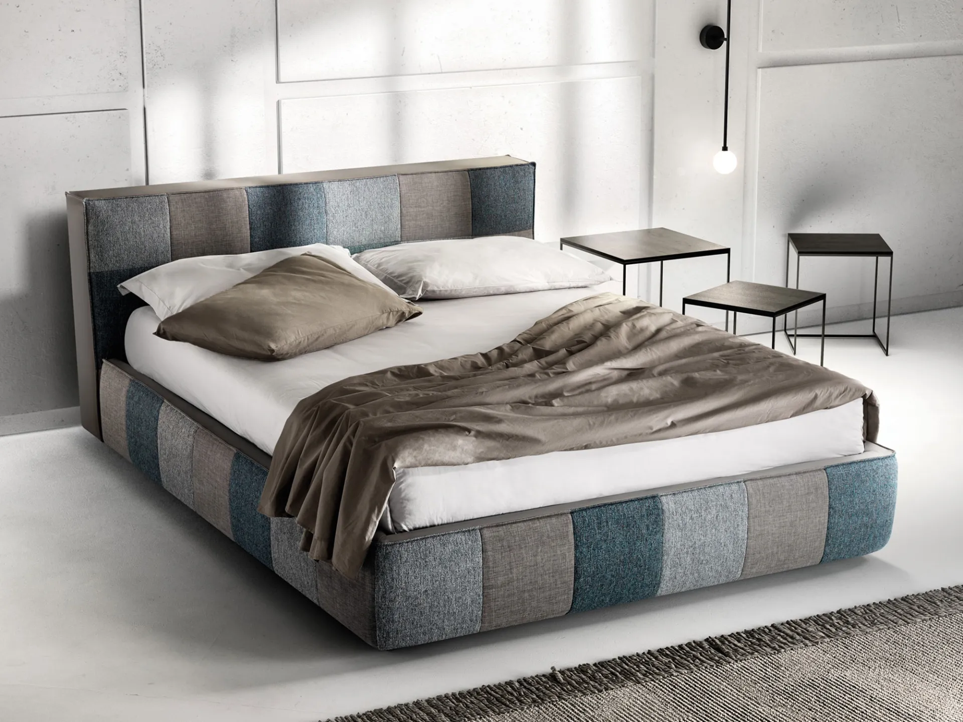 Letto imbottito Square Samoa a blocchi in tessuti grigi e blu, accanto a tavolini in metallo