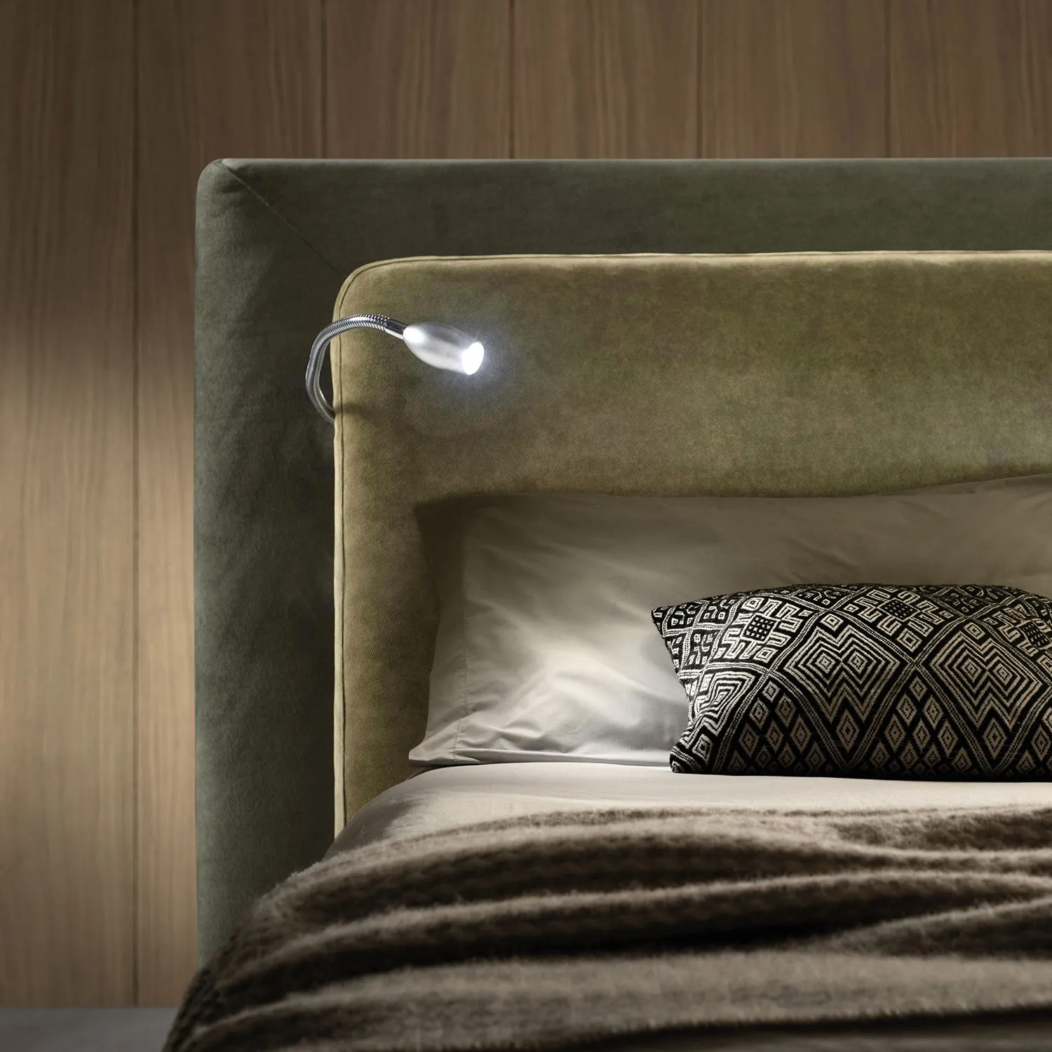 Luce di lettura a led su braccio flessibile montata sulla testiera verde del letto Flux Samoa