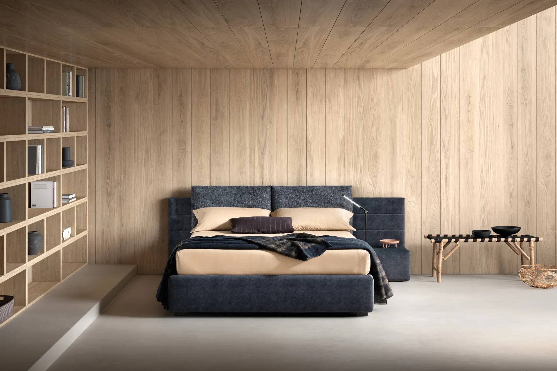 Letto imbottito Smash Samoa blu scuro con testiera larga e comodini imbottiti, in una camera rivestita in legno