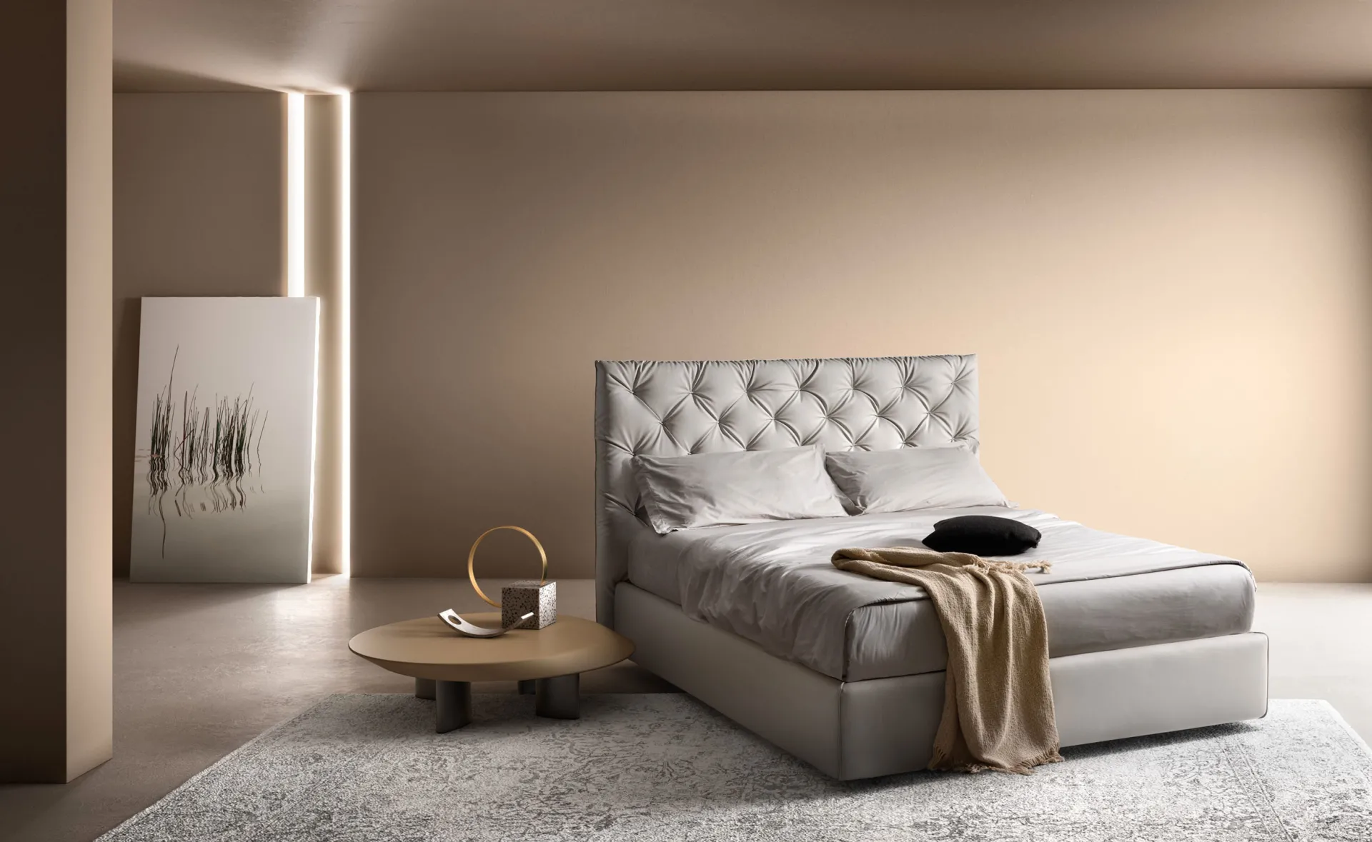 Letto imbottito Tender Samoa grigio perla con testiera capitonné, accanto a un tavolino rotondo