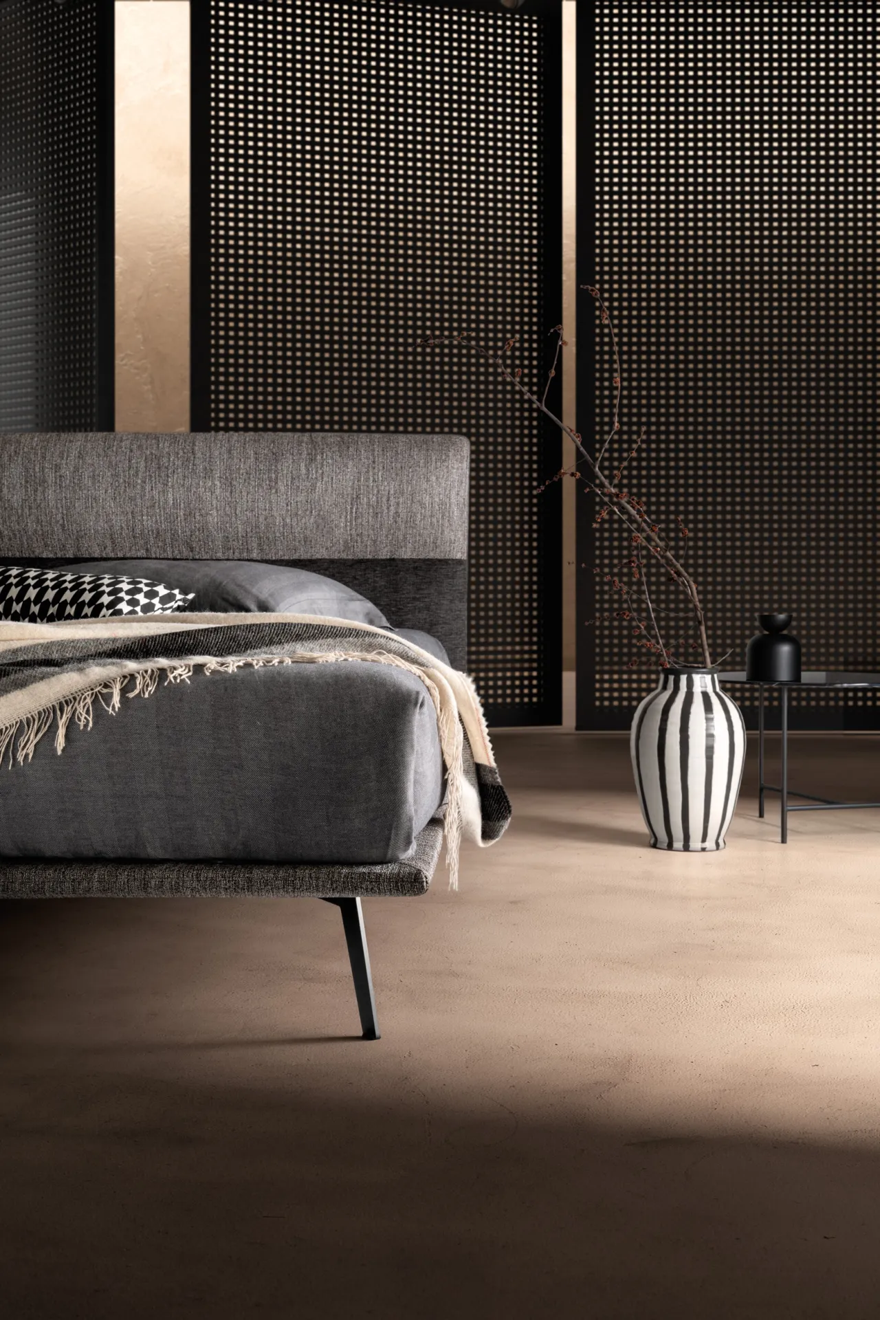 Letto Dance Samoa visto di lato, con giroletto sottile e vaso a righe sul pavimento