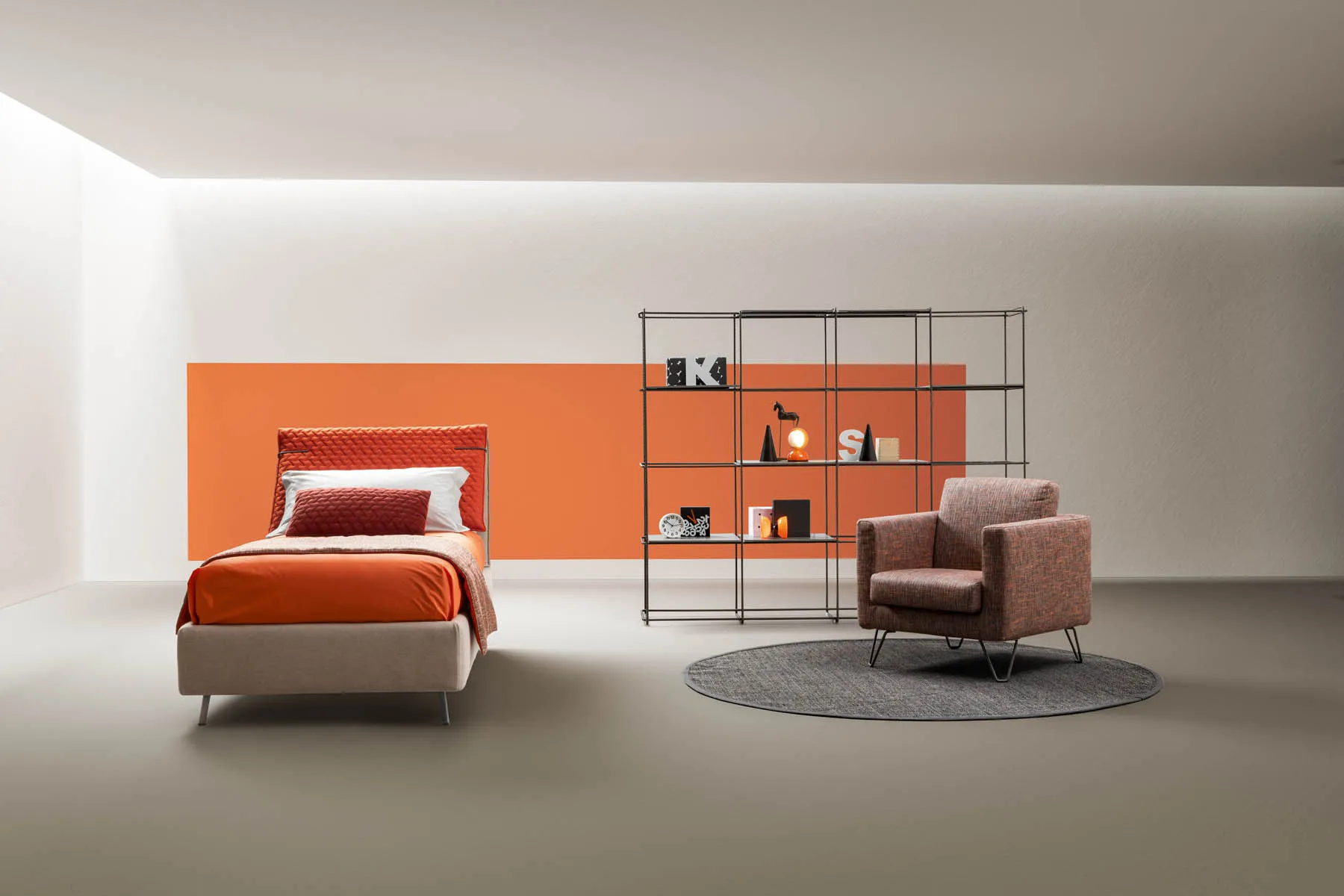 Letto singolo Spin Samoa arancio e sabbia in una cameretta con libreria in metallo e poltroncina