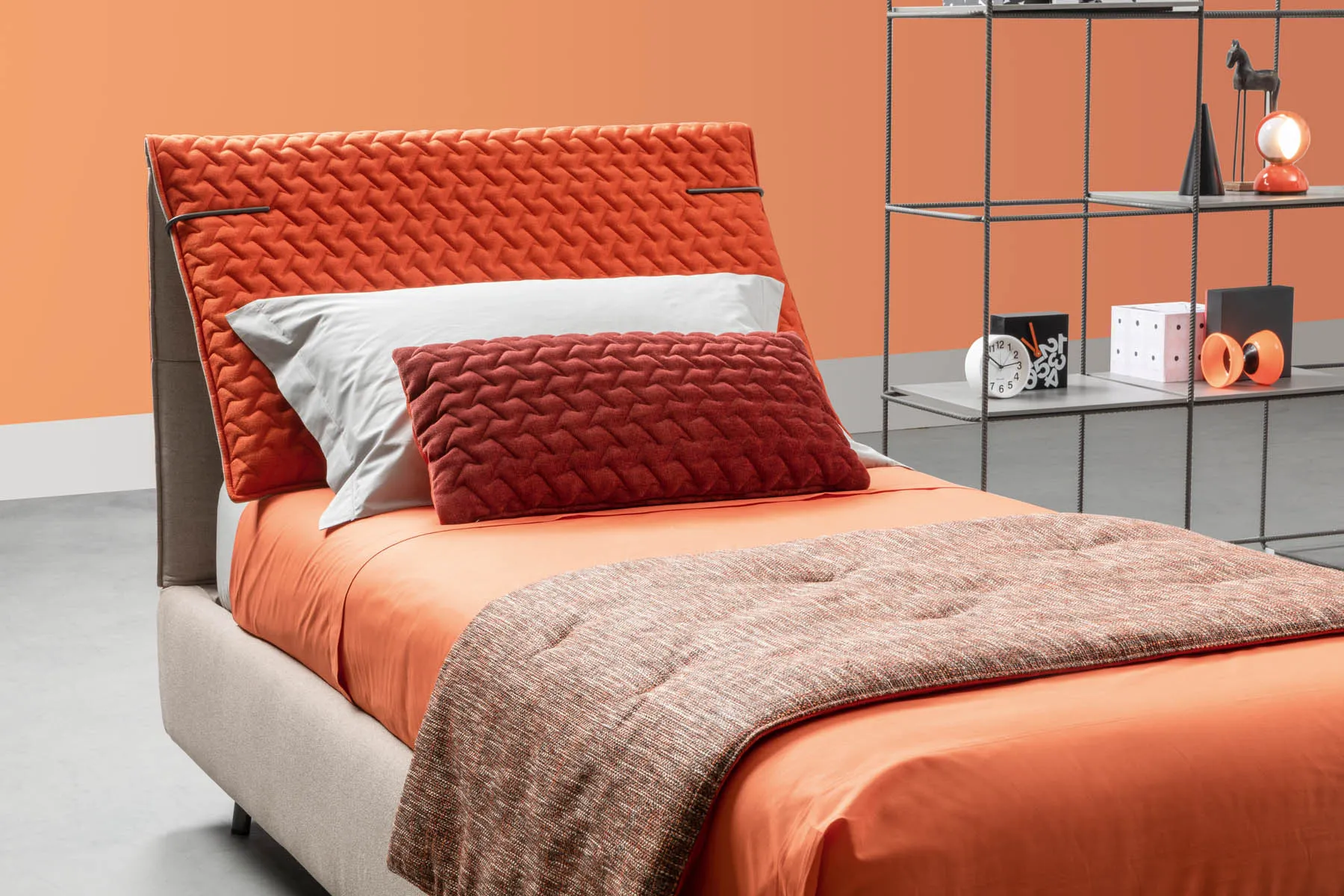 Testiera del letto Spin Samoa con la fodera arancio trapuntata a onde e la cinghietta laterale
