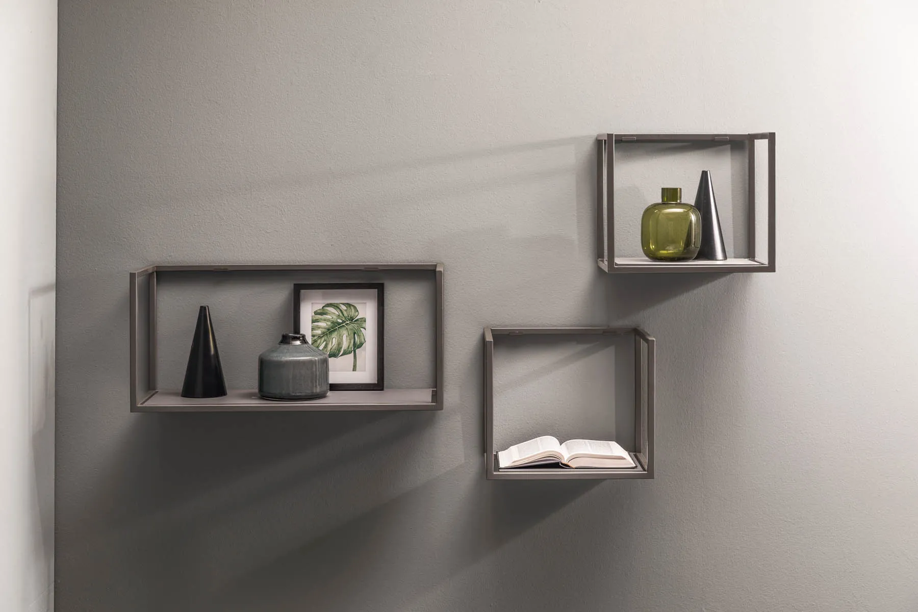Moduli libreria Frame Samoa a telaio grigio appesi a parete con oggetti e libri