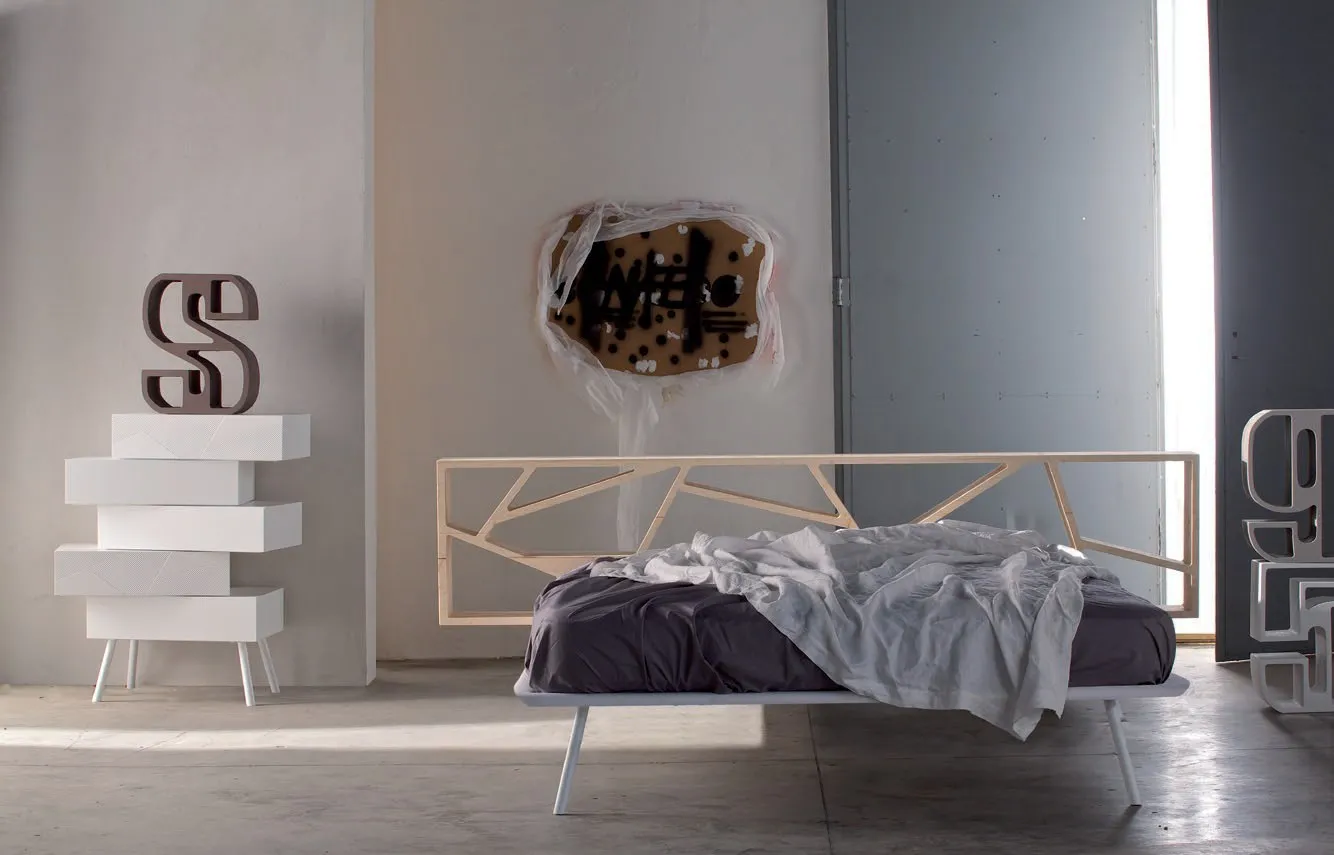 Letto Space Voltan con testiera a giorno in tinta chiara accanto a una cassettiera a cassetti sfalsati