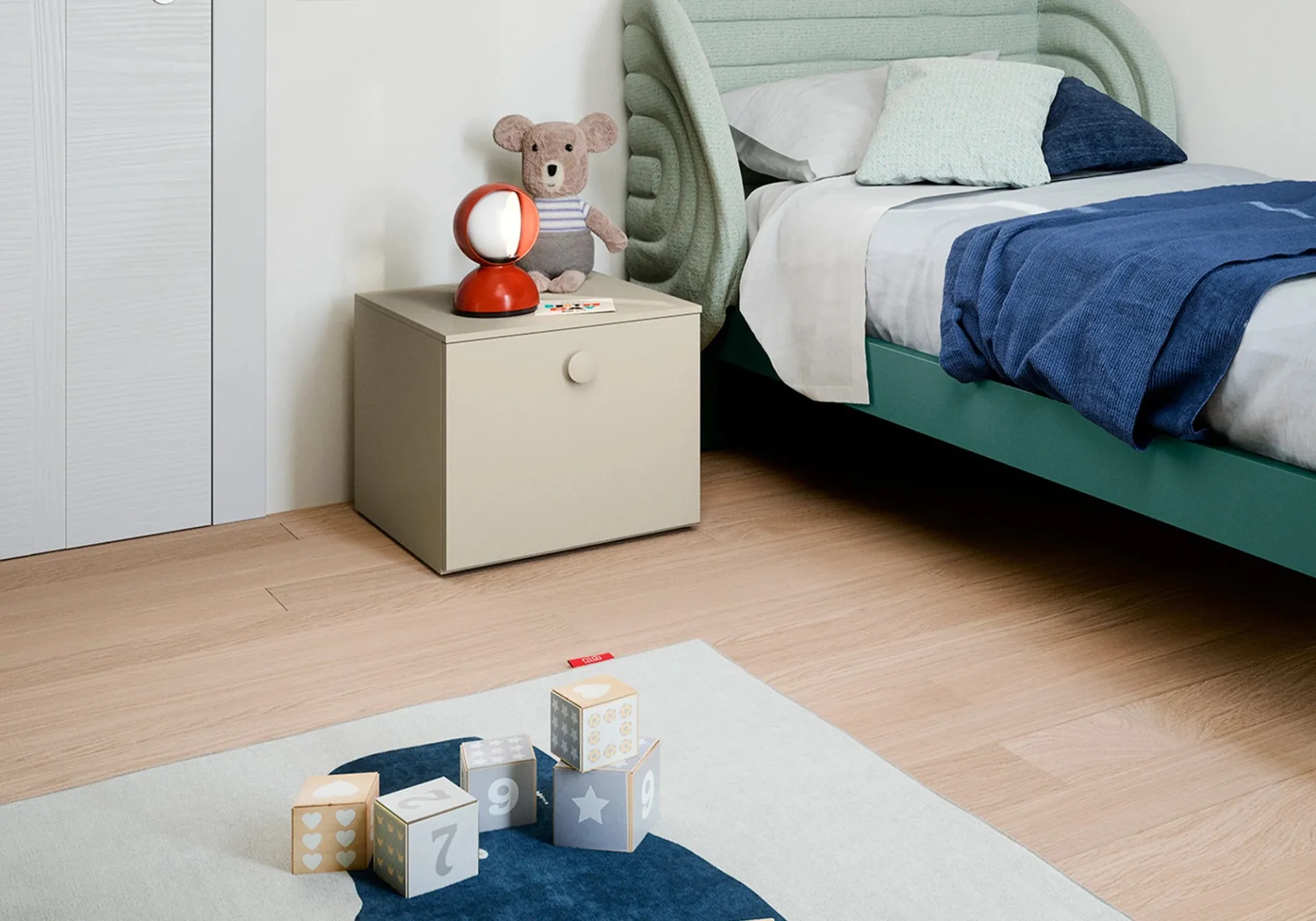 Comodino componibile Nidi beige con un cassettone accanto al letto verde