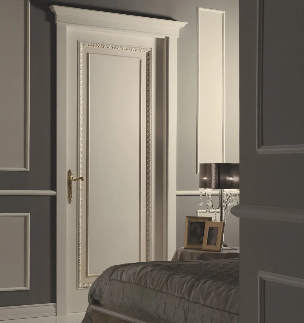 Porta interna Componibile Bernazzoli bianca con cornice e profilo dorato in una camera grigia