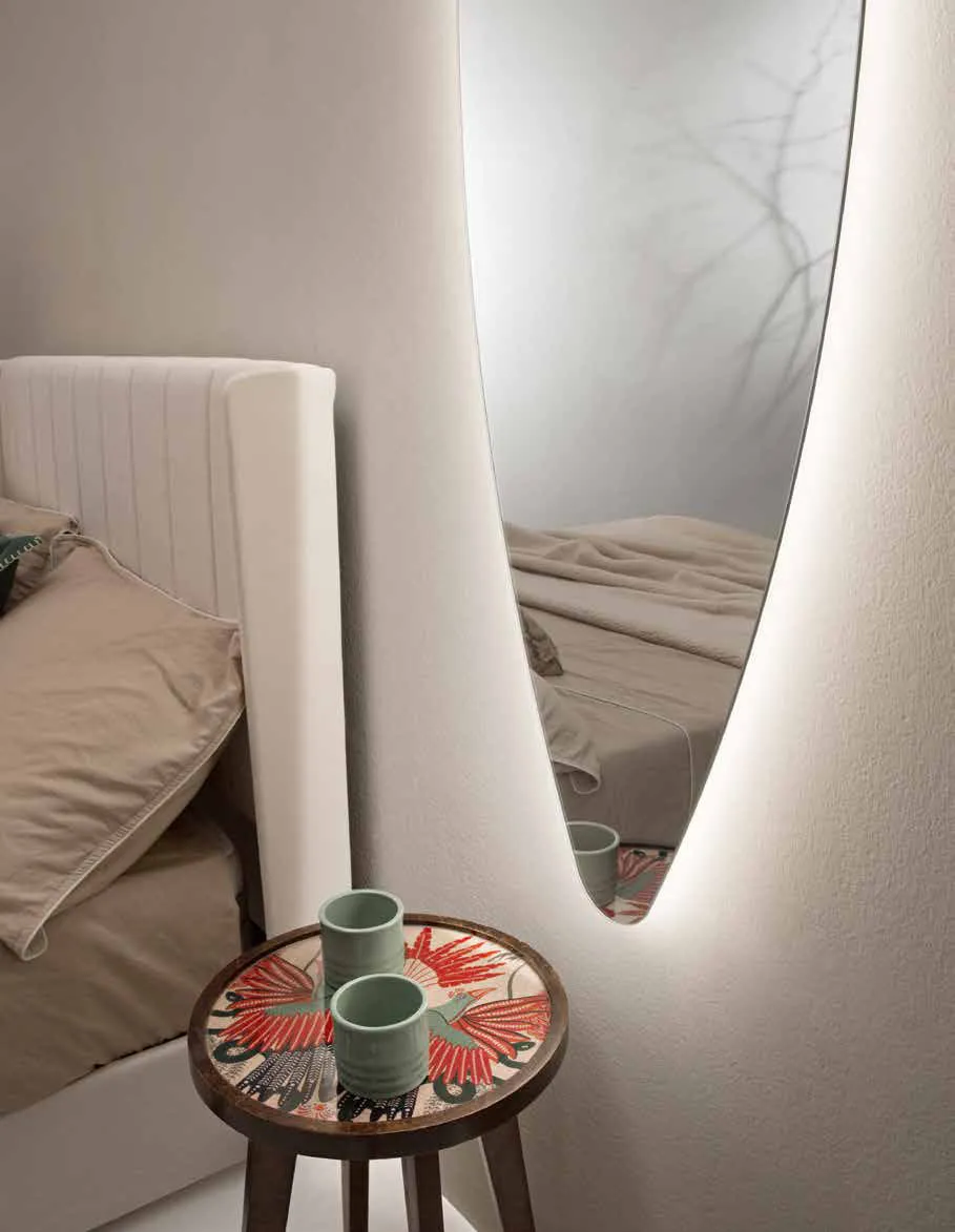 Specchio Rem Fan Europe retroilluminato accanto a un letto