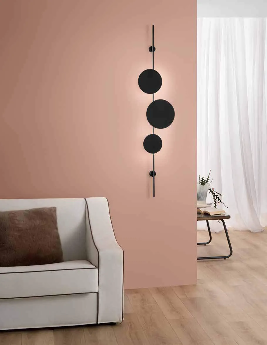 Applique Idol Fan Europe nera verticale su parete rosa sopra un divano