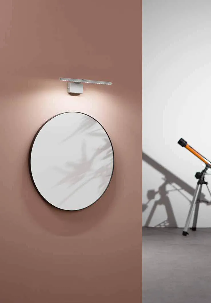 Applique Alcor Fan Europe sopra uno specchio tondo su parete rosa