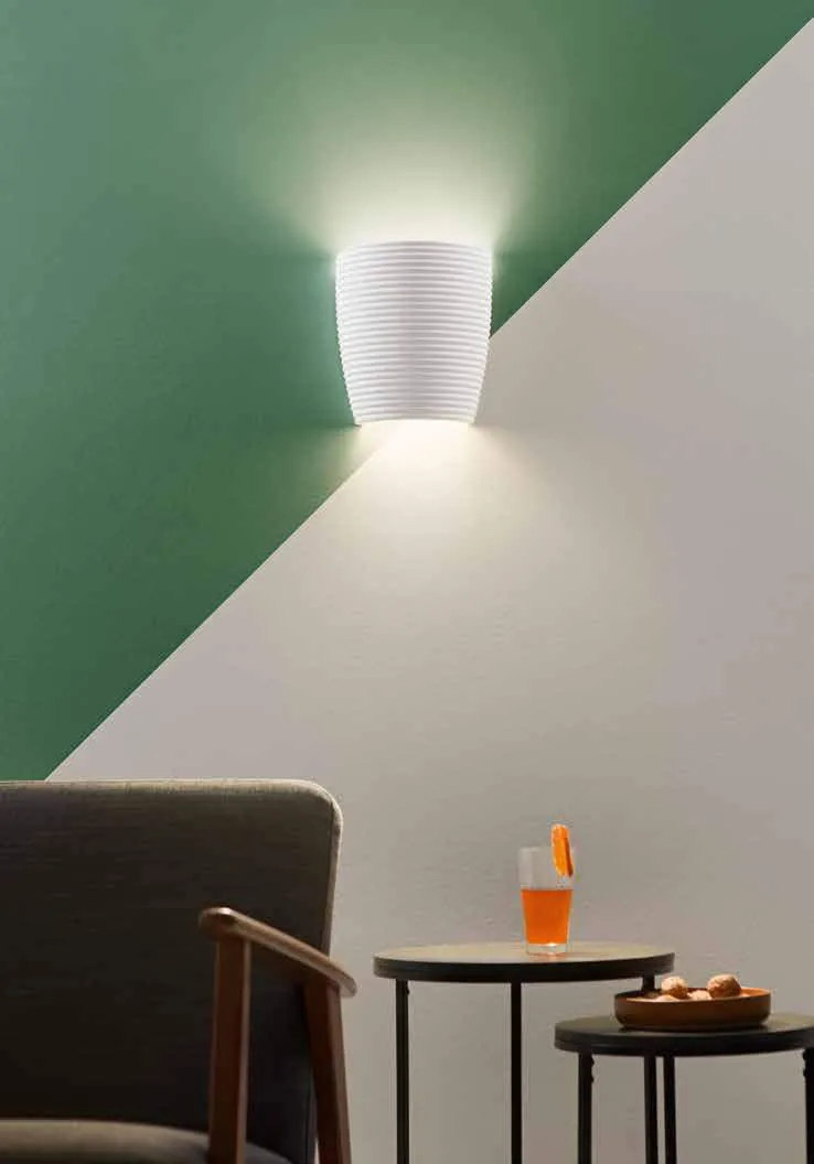 Applique Corinto Fan Europe su parete verde e bianca sopra un tavolino