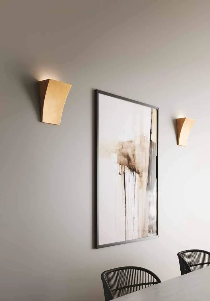 Due applique Alma Fan Europe oro ai lati di un quadro in una sala da pranzo