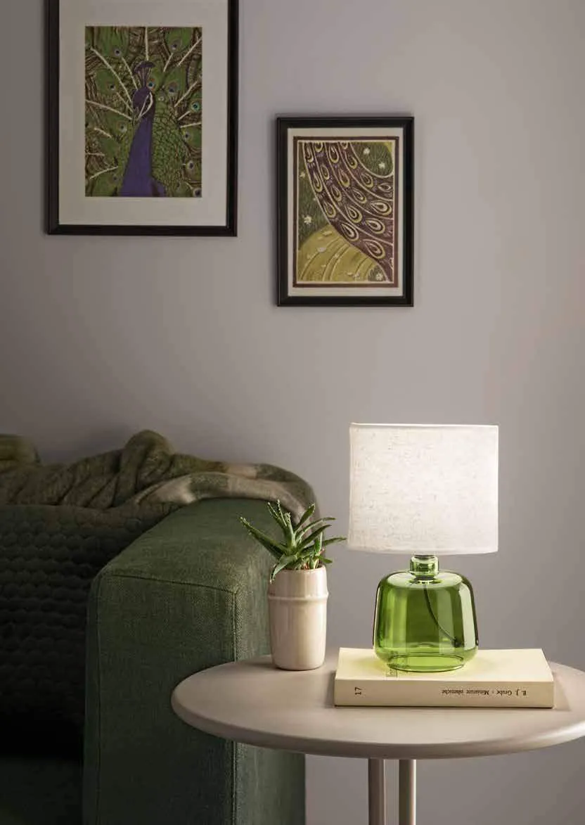 Lampada da tavolo Emerald Fan Europe con base in vetro verde accanto a un divano