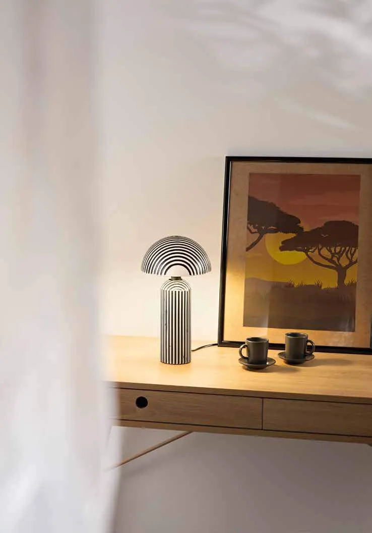 Lampada da tavolo Tanzania Fan Europe a cupola su un mobile accanto a un quadro