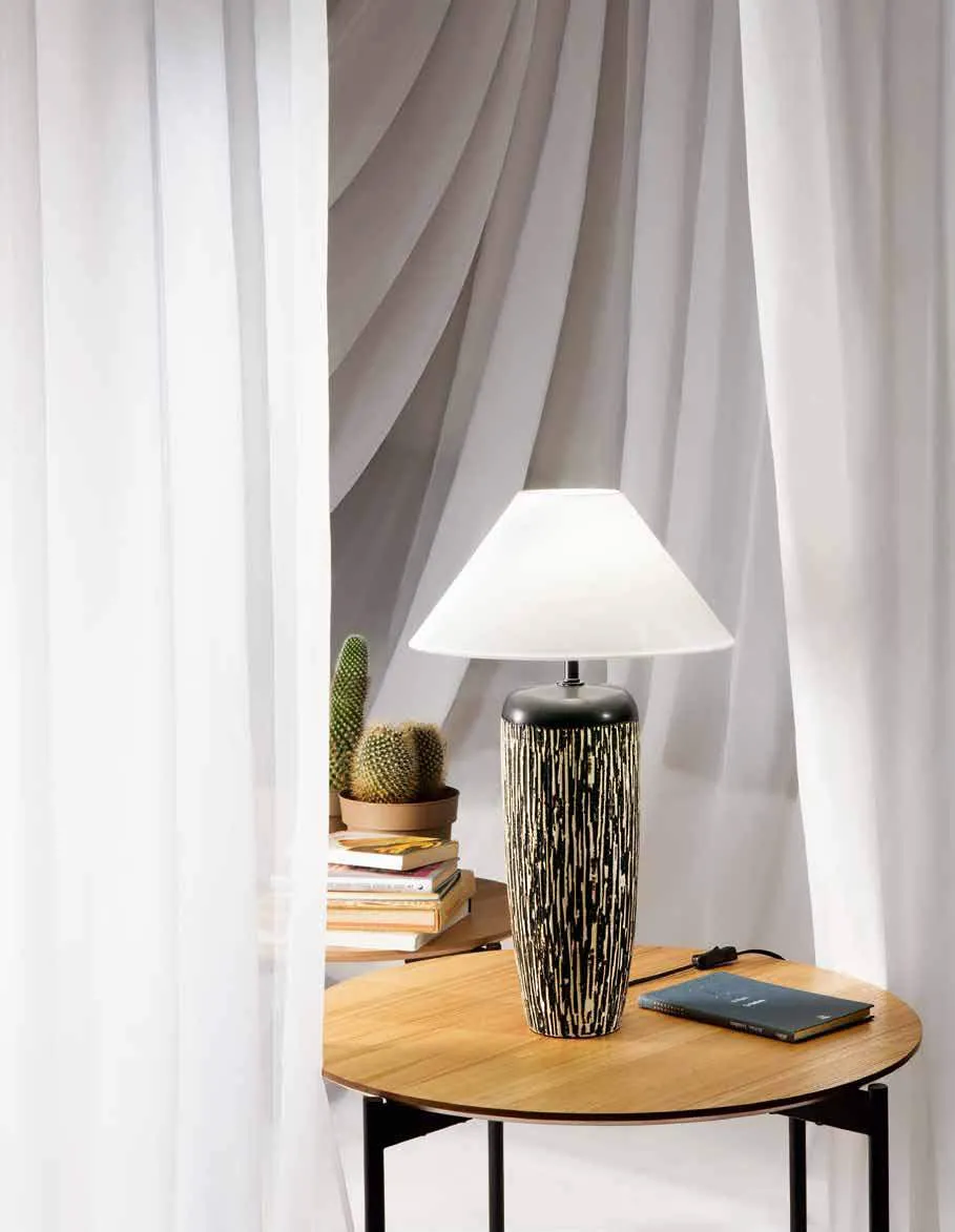 Lampada da tavolo Savana Fan Europe con base decorata accanto a una tenda