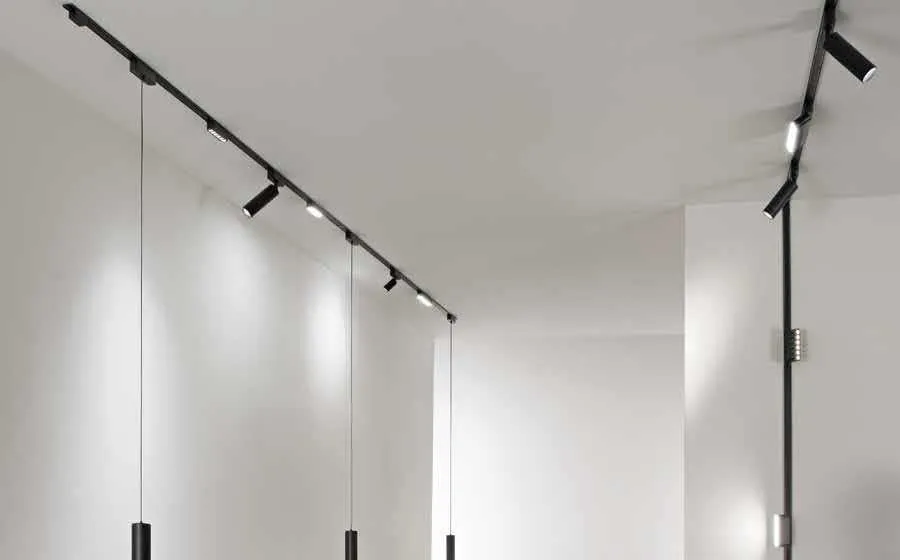 Binario Bernini 48V Fan Europe nero a soffitto con faretti e sospensioni lungo un corridoio bianco