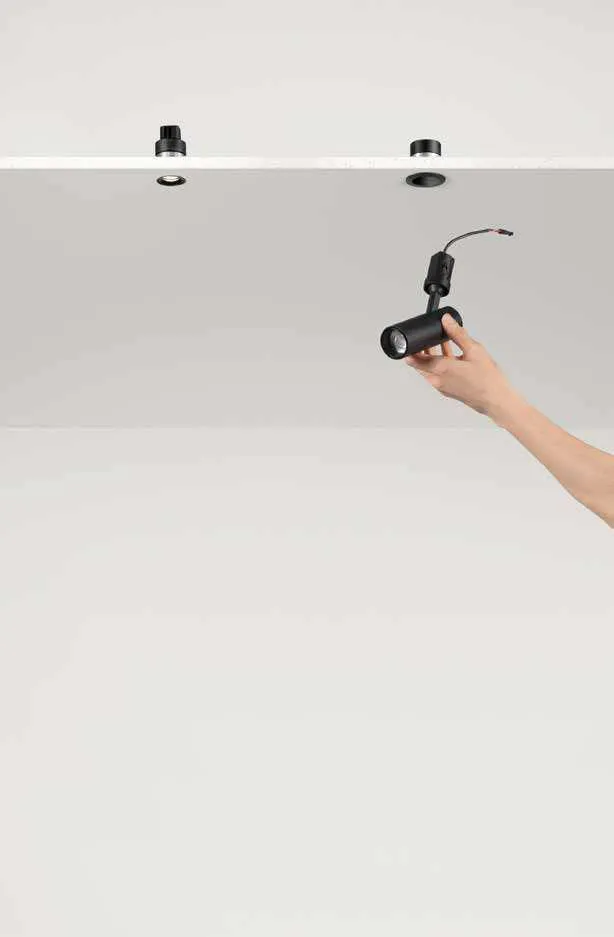 Mano che inserisce un faretto Shift Fan Europe nell'alloggio a incasso del soffitto