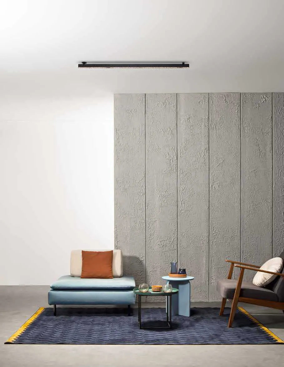 Lampada lineare Shift Linear Fan Europe a soffitto sopra un soggiorno con divanetto e tappeto blu