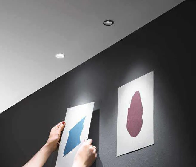 Faretti da incasso Dot Fan Europe che illuminano due stampe su una parete nera
