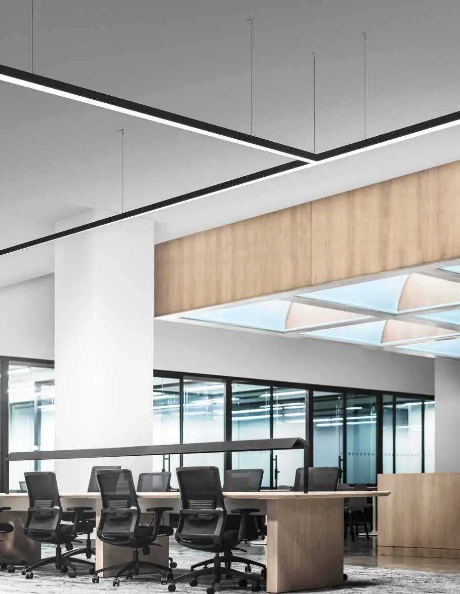 Barre LED Next Fan Europe nere collegate in linee sospese sopra le scrivanie di un ufficio