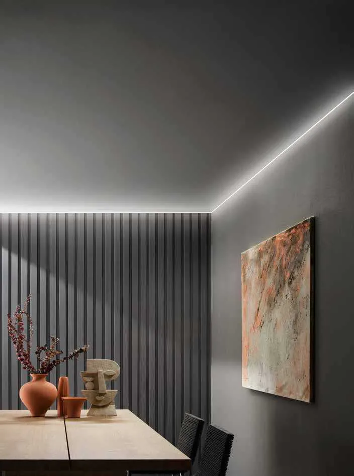 Taglio di luce Edge Fan Europe lungo il soffitto in una sala da pranzo con parete a doghe