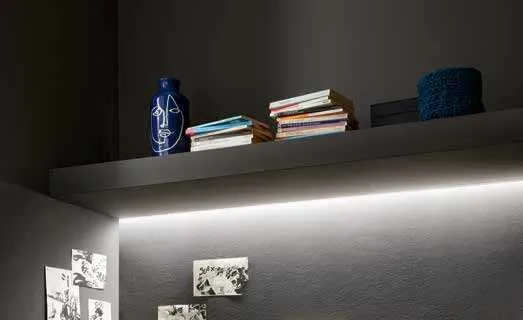 Mensola con profilo Incro Fan Europe acceso che illumina una parete scura con disegni