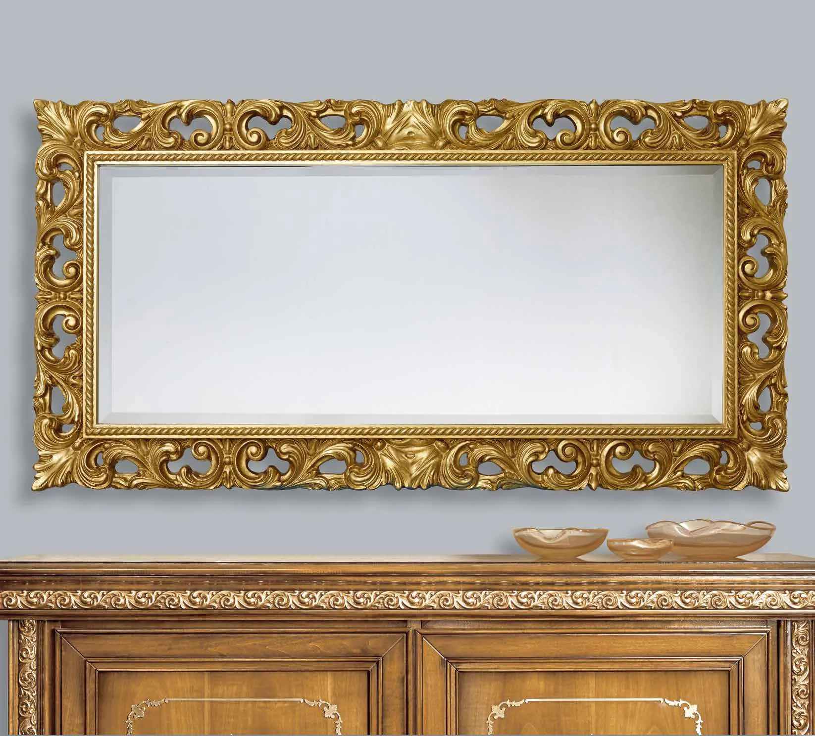 Specchiera SP 6320 Imba dorata traforata a volute sopra una credenza in noce
