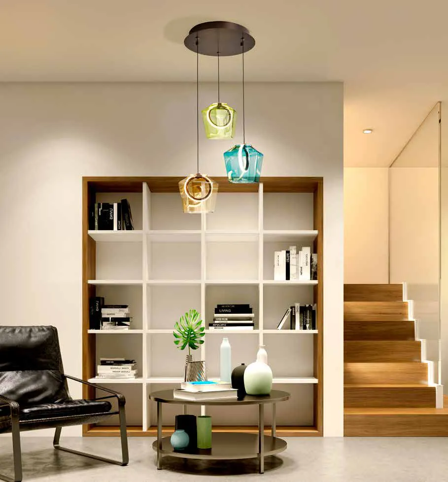 Lampada Ingrid Schuller a 3 luci verdi, blu e champagne vicino a una libreria