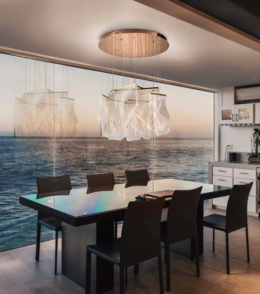 Lampada Velos Schuller oro rosa sopra un tavolo da pranzo davanti al mare