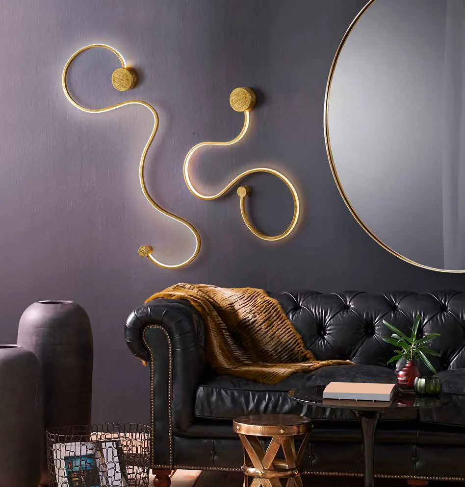 Applique Grafos Schuller in foglia oro sopra un divano Chesterfield
