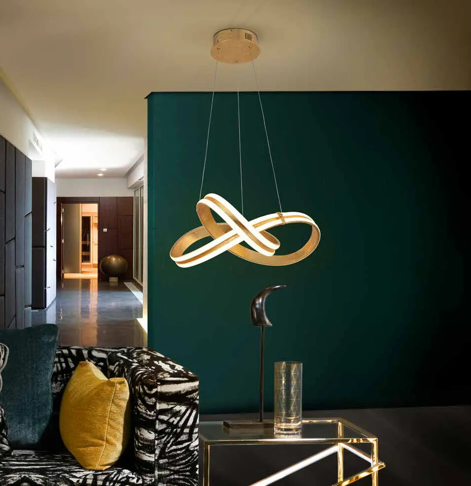 Sospensione Lazas Schuller a nodo in foglia oro davanti a una parete verde
