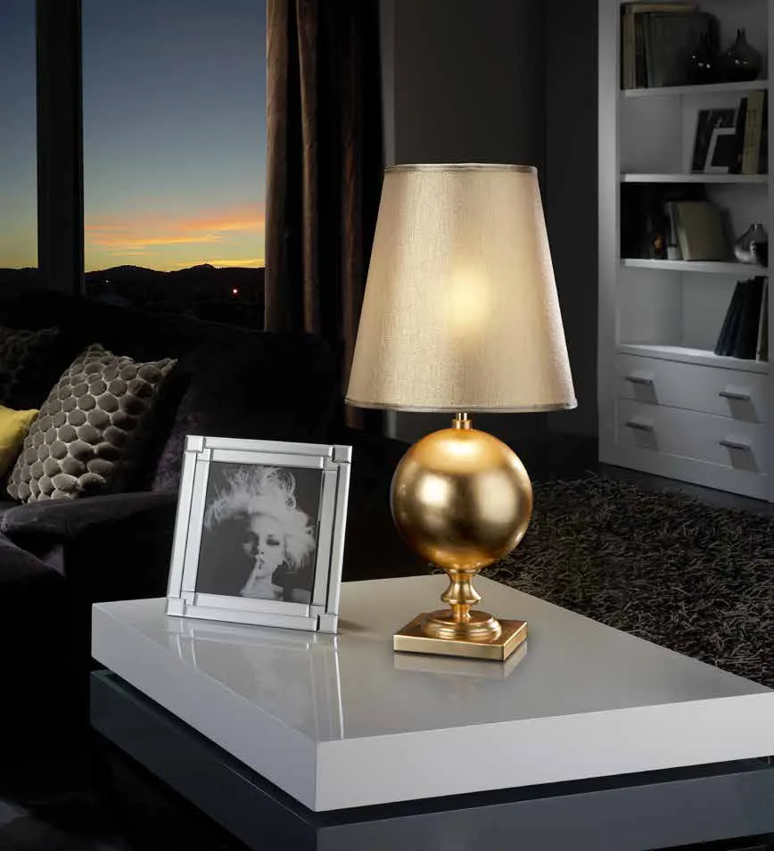 Lampada da tavolo Terra Schuller con base a sfera foglia oro su un tavolino bianco