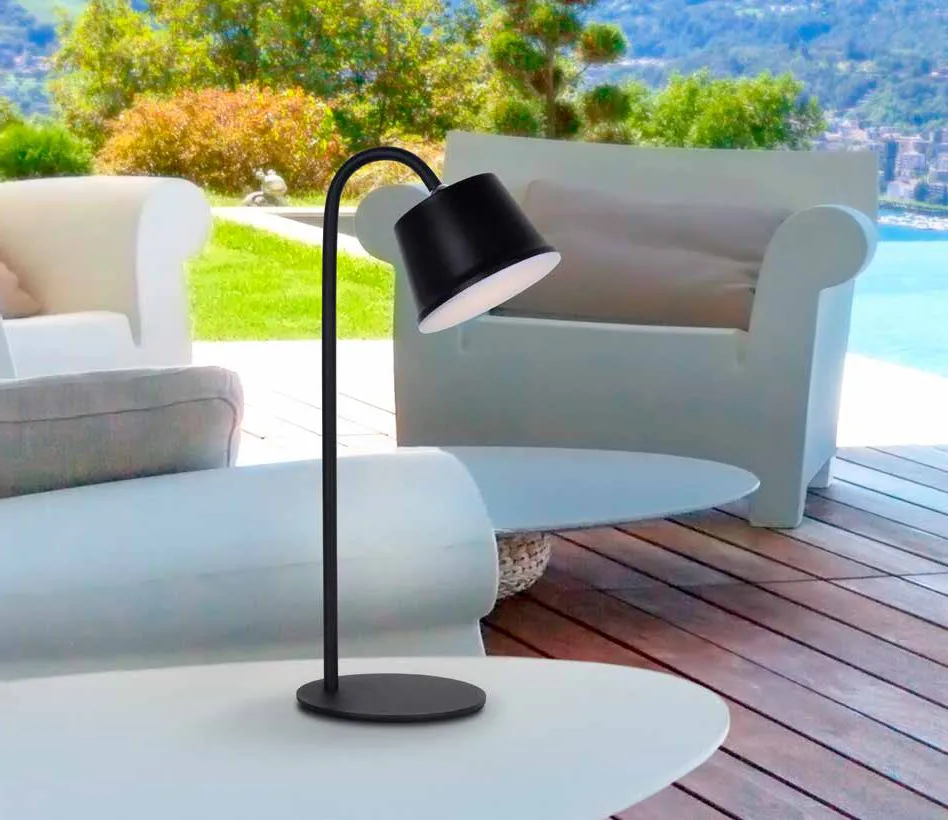 Lampada portatile Cuco Schuller nera su un tavolino in giardino