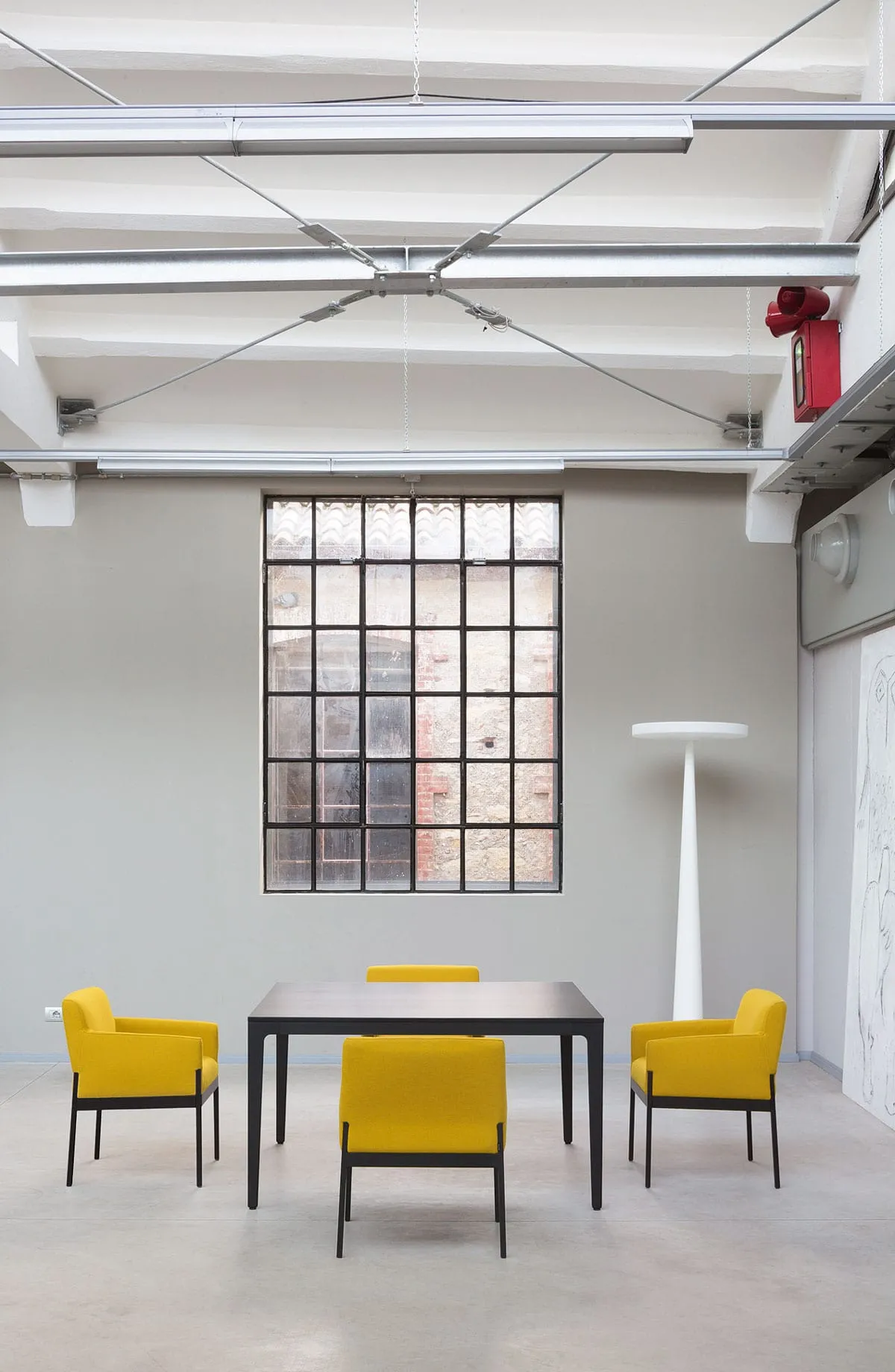 Poltroncine Stand By Armchair Frezza gialle attorno a un tavolo in un loft