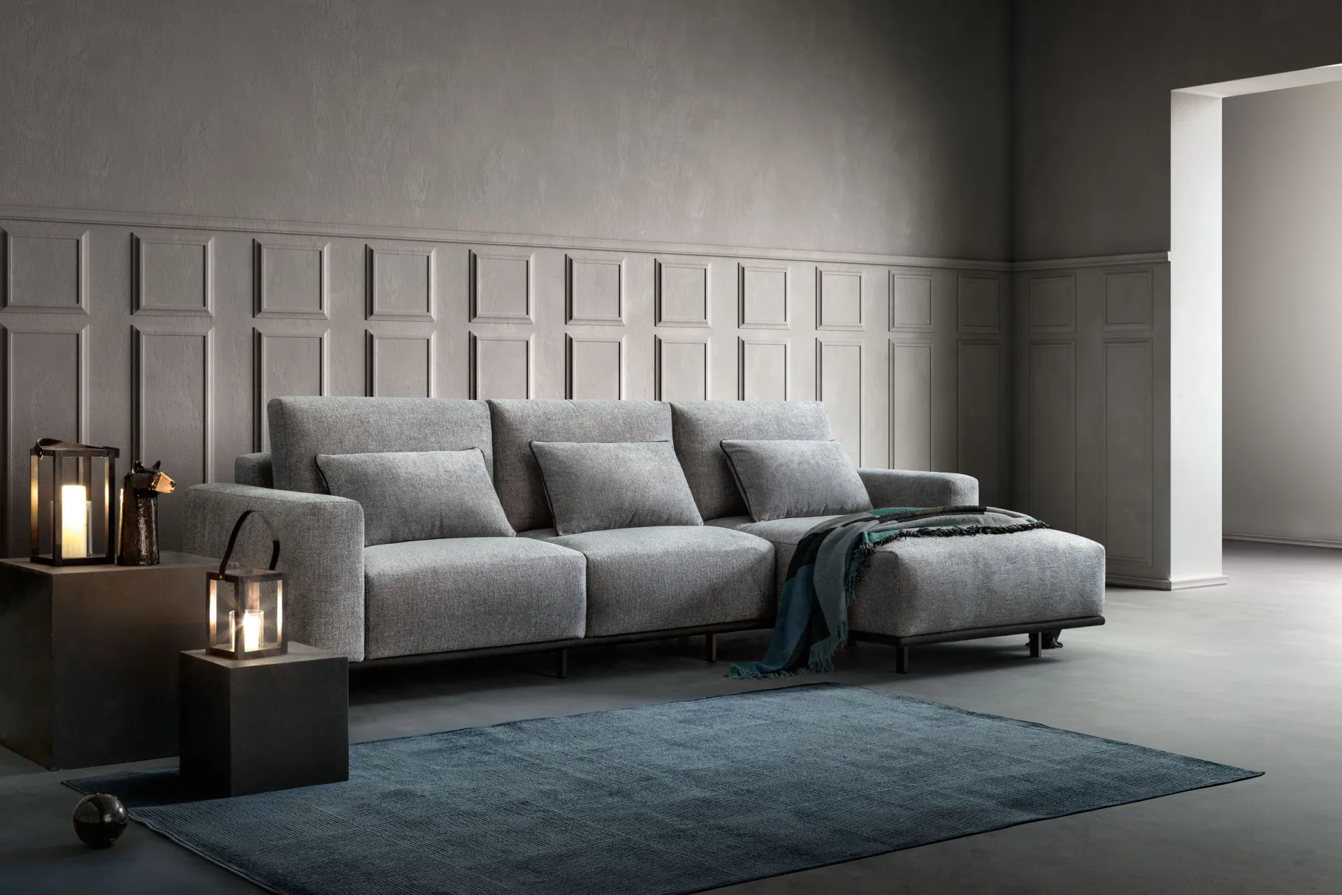Divano componibile Ginny Samoa grigio in versione lineare con chaise longue, davanti a una parete a riquadri