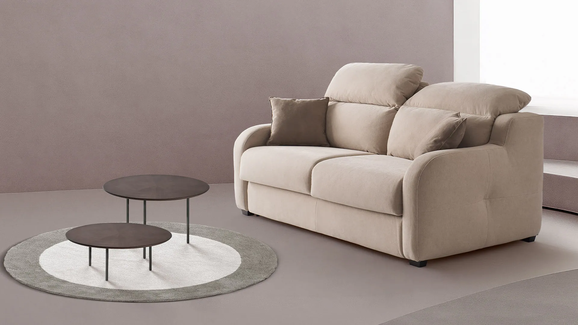Divano letto Astoria Aerre Divani beige su tappeto tondo con tavolini scuri, parete rosa antico