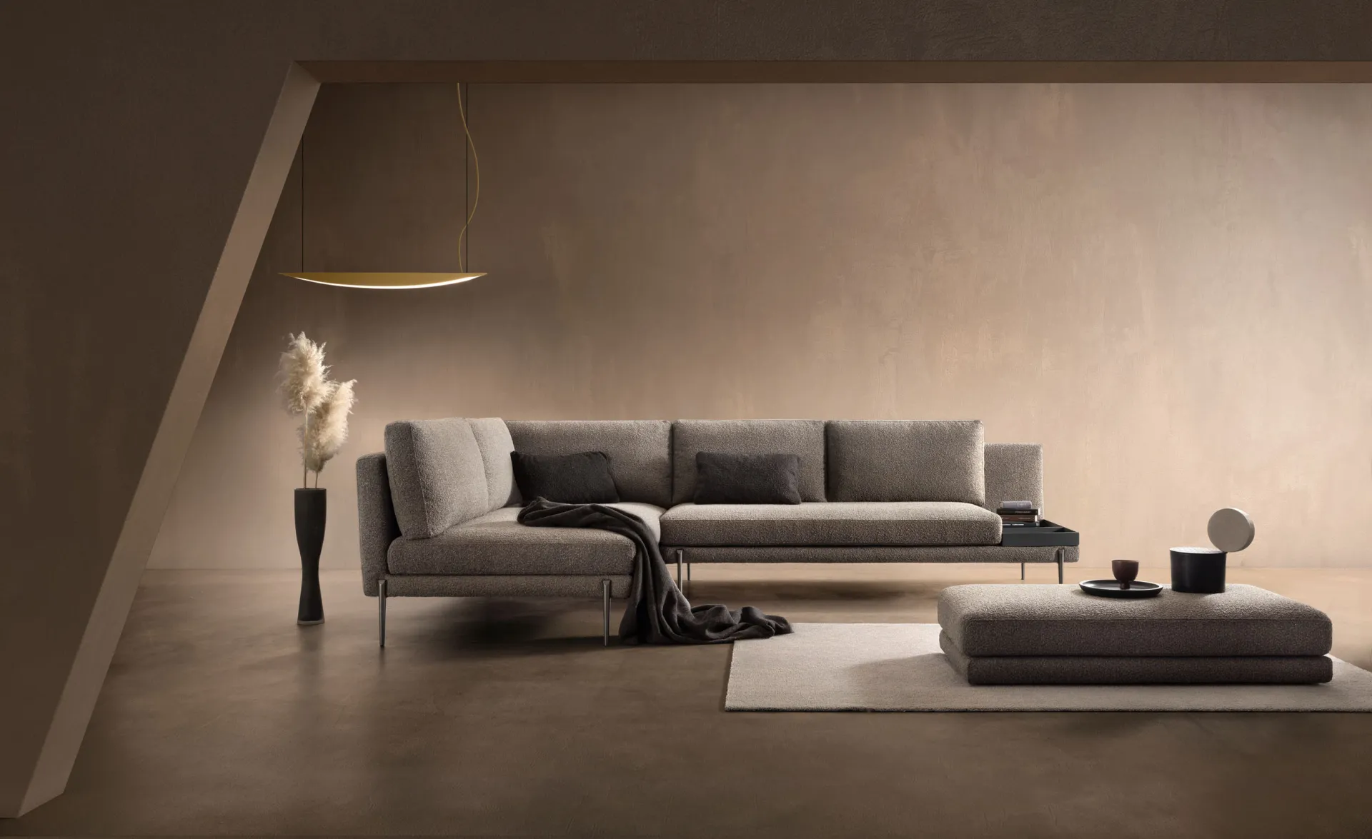 Divano componibile Wise Samoa grigio con modulo aperto e pouf, in un soggiorno dai toni caldi